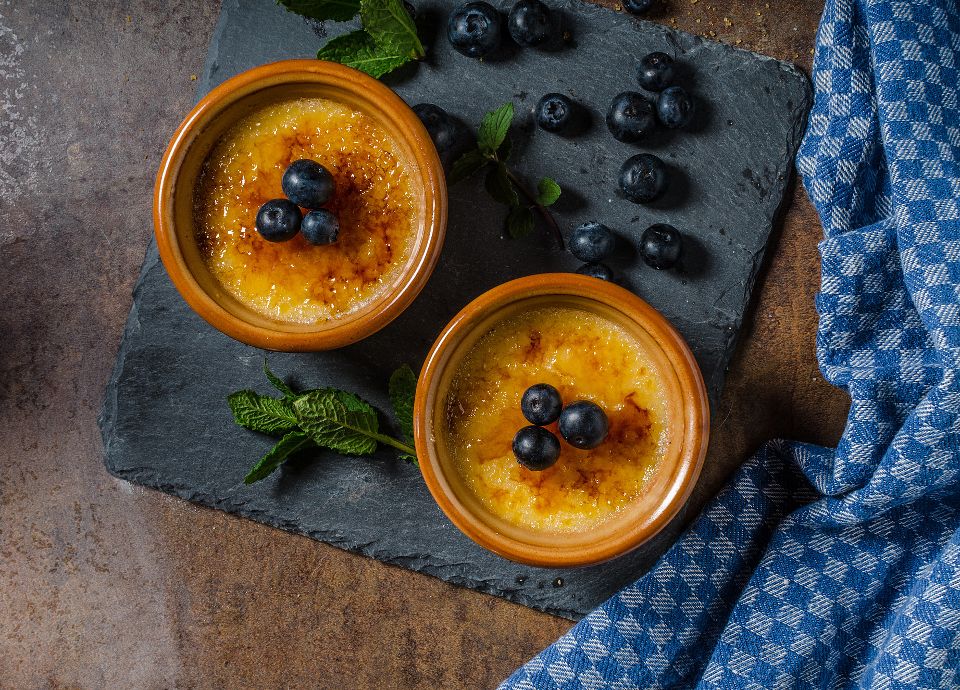 Close-up of a crème brûlée in a white ramekin with a crisp, golden-brown caramelized sugar topping.