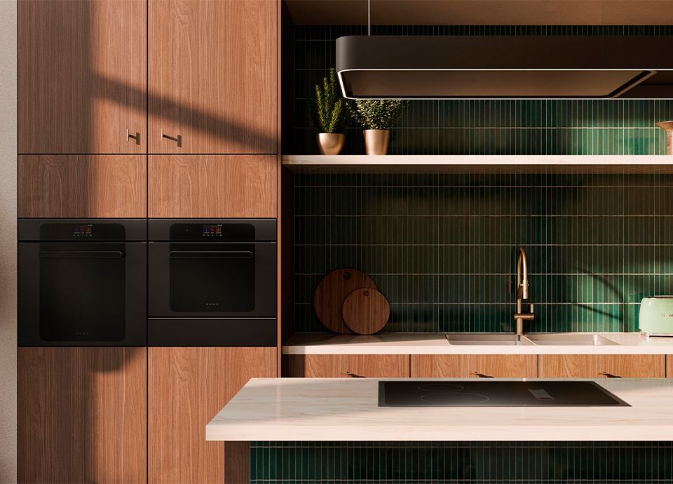 Contemporary kitchen with wooden cabinetry, black built-in ovens and induction hob, green tiled backsplash and island hood