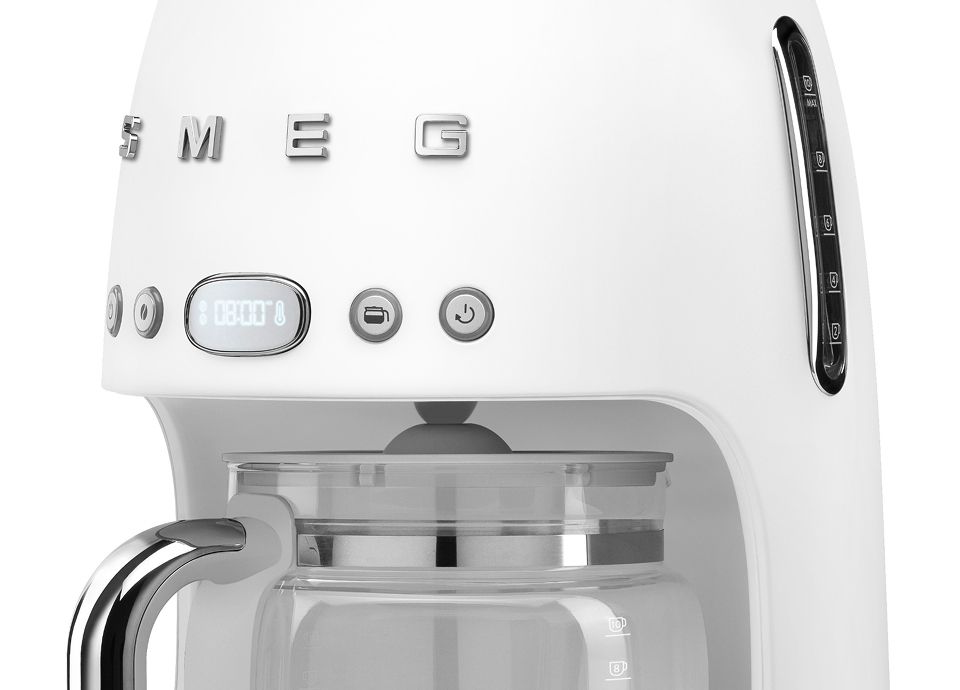 Close-up of white matte drip filter coffee machine with control buttons and glass carafe