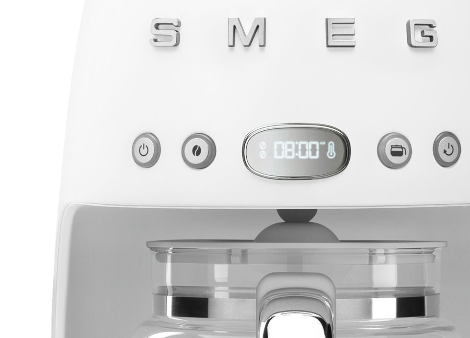 Close-up of a white matt-finish drip coffee machine showing the LED display, function buttons, and glass carafe handle.