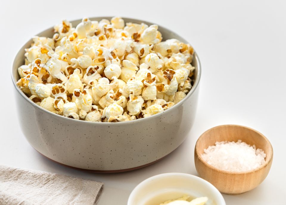 Popcorn in a gray ceramic bowl with a small bowl of salt and a gray cloth napkin.