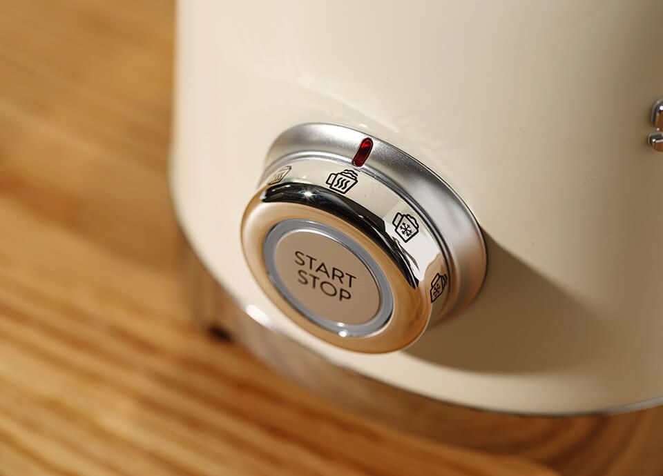 Close-up of a cream SMEG milk frother control knob with Start/Stop button and icons for different heating and frothing functions.