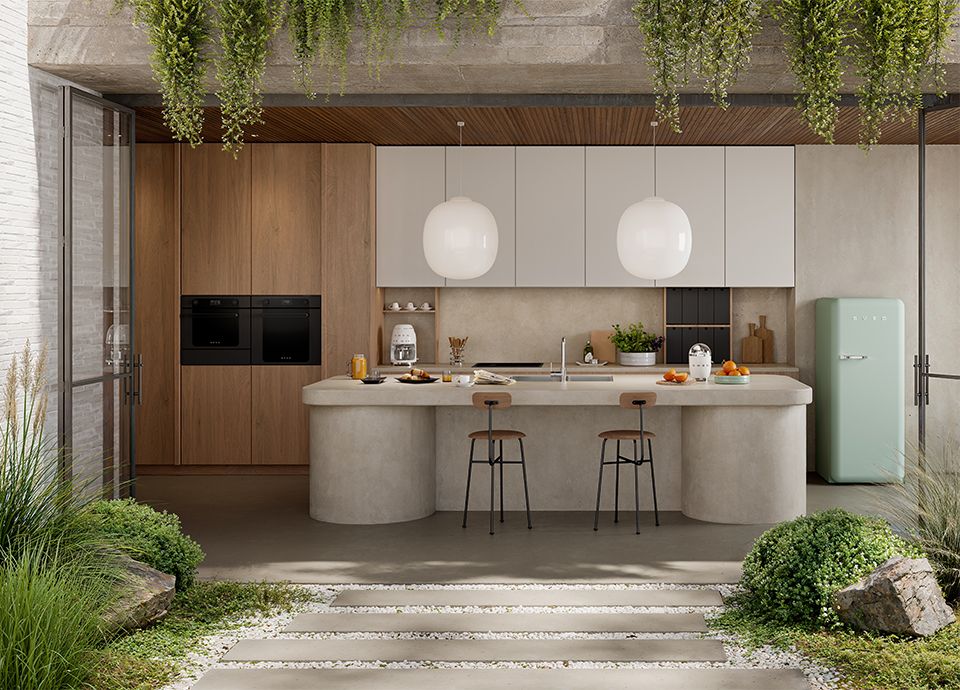 Modern kitchen with a concrete island, wooden cabinets, white wall units, and hanging plants.