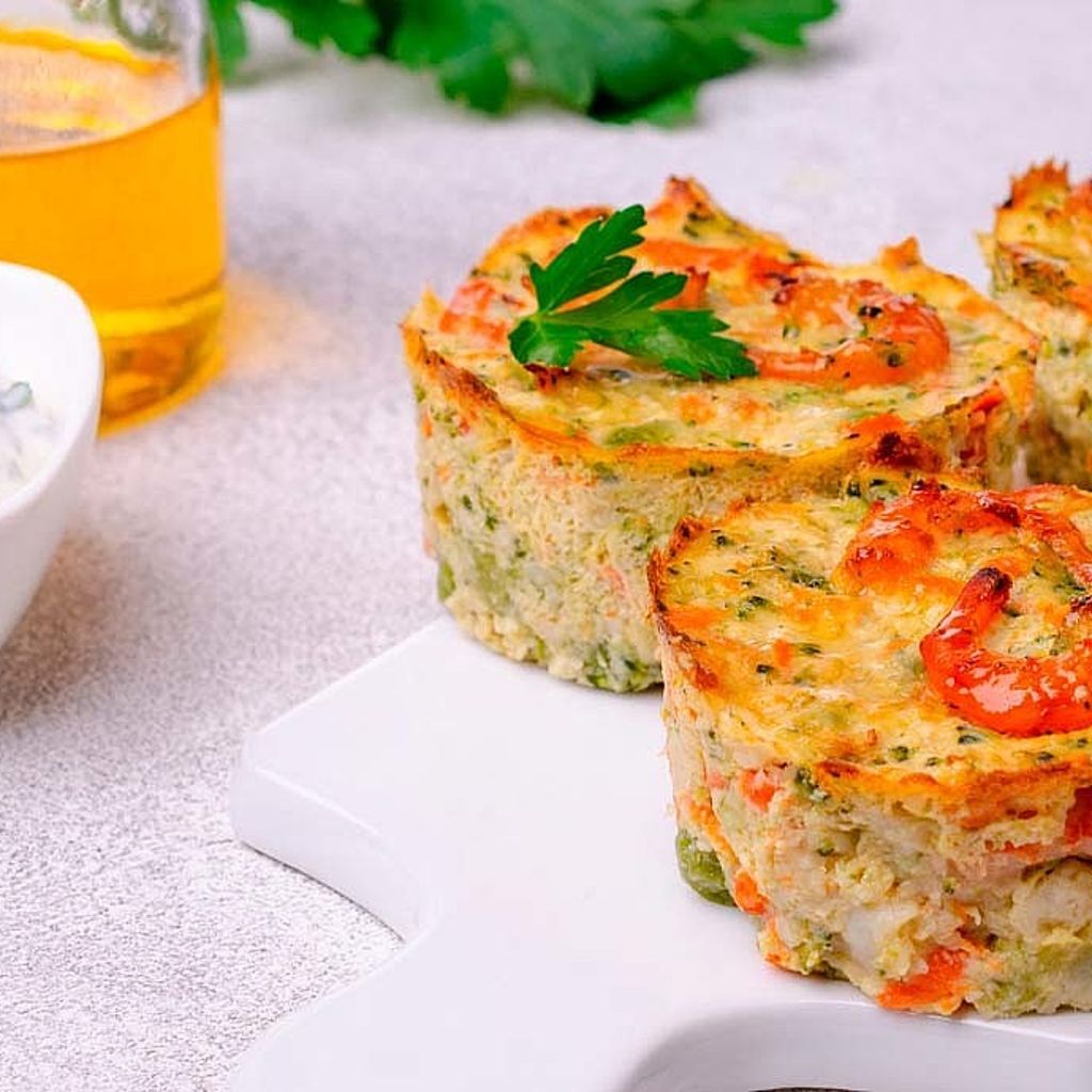 A delicate zucchini flan topped with a whole grilled shrimp and a sprig of fresh chervil, served on a white plate.