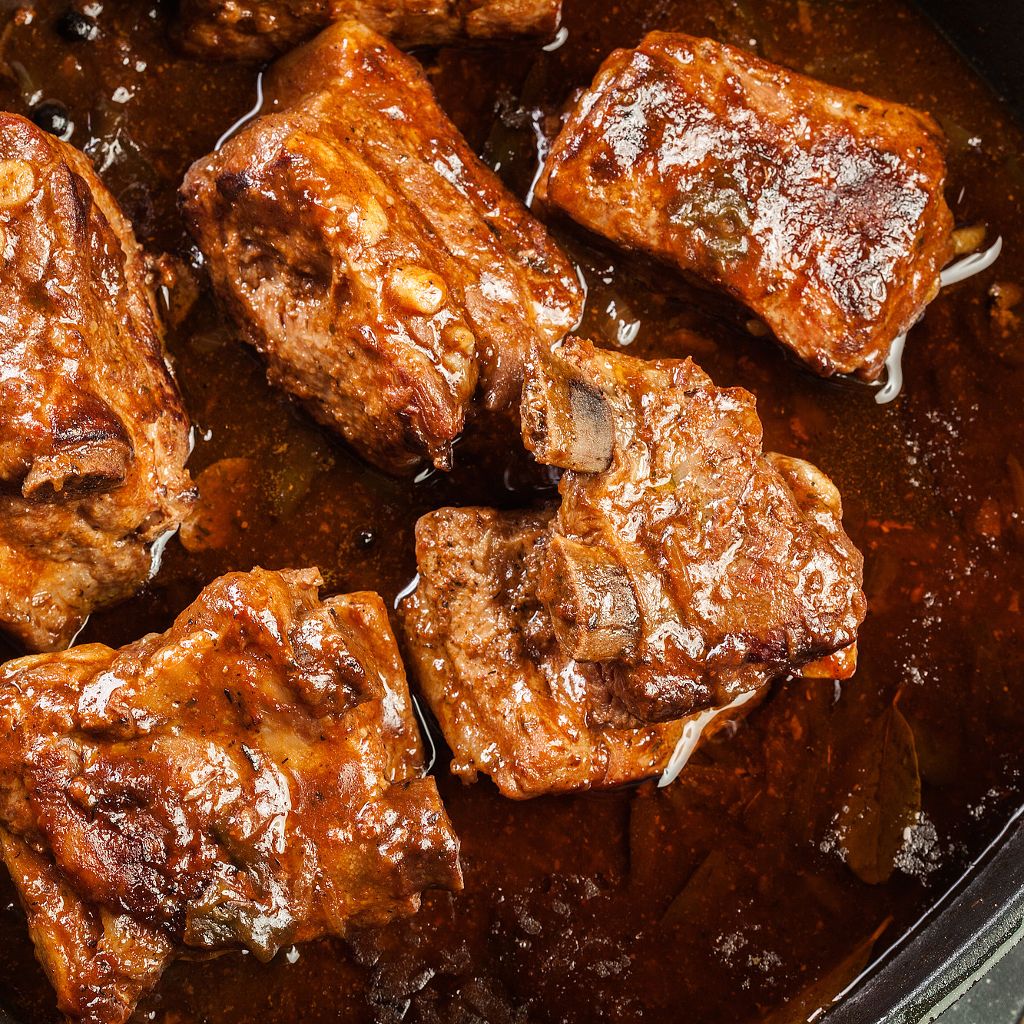 Close-up of tender, glazed pork ribs simmered in a rich, dark brown sauce.