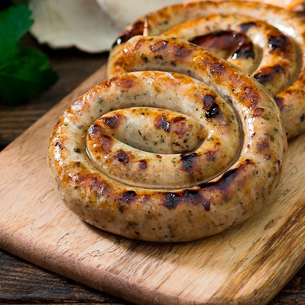 Two golden-brown, spiral-shaped baked sausages with char marks served on a light wooden board.