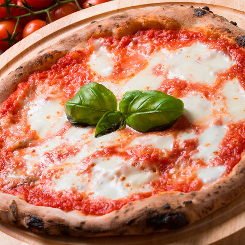 Fresh Margherita pizza with bubbly mozzarella, tomato sauce, and basil leaves on a round wooden board.